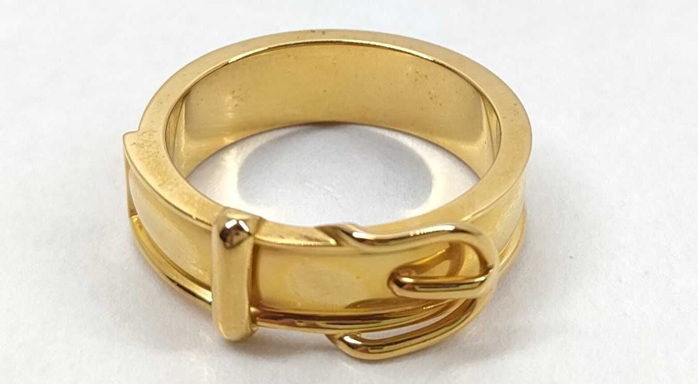 A yellow gold ring with a textured, multi-band design and a small decorative element on the front, photographed on a plain white background.