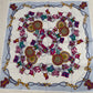 Decorative scarf with intricate patterns and chains on a wooden surface