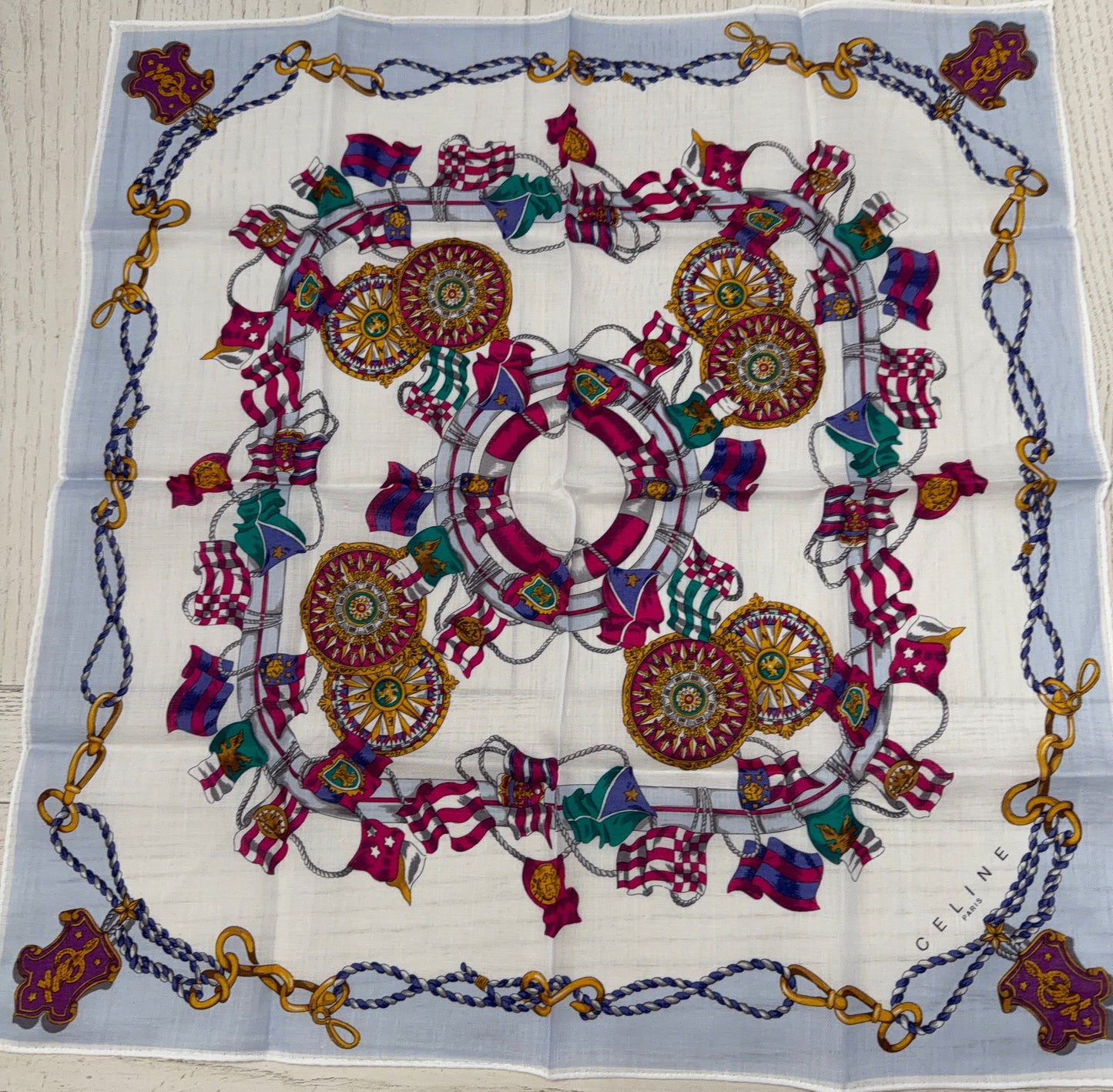 Decorative scarf with intricate patterns and chains on a wooden surface